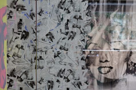The left half of the glass front door to The Warhol museum is plastered with black and white papers. The right side of the door is still uncovered, and through it the black and white portrait of Marilyn Monroe is visible in the Warhol lobby.